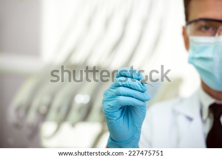 Close-up portrait of young professional handsome dentist in medical uniform and dentist tools.