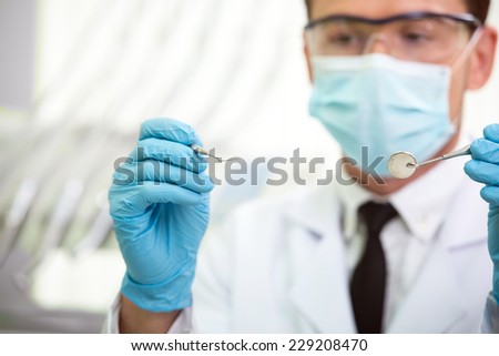 Portrait of young professional handsome dentist in medical uniform and dentist tools.
