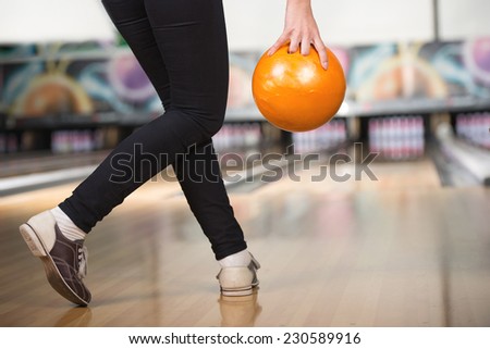 Young woman is playing bowling, preparing to throw ball.