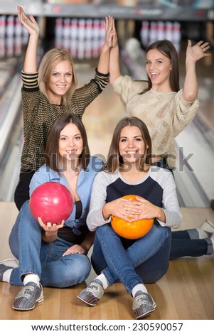 Young emotional group of female friends in bowling alley with balls.