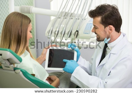 Portrait of friendly doctor and patient with tablet at dentist\'s office.