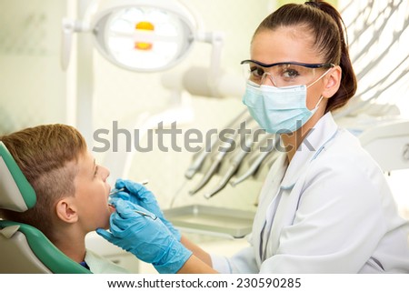 The female doctor treats a tooth of little boy at dentist\'s clinic.