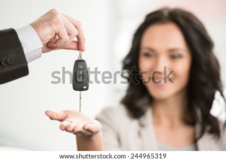 Happy woman receives the keys to a new car from a sales manager.