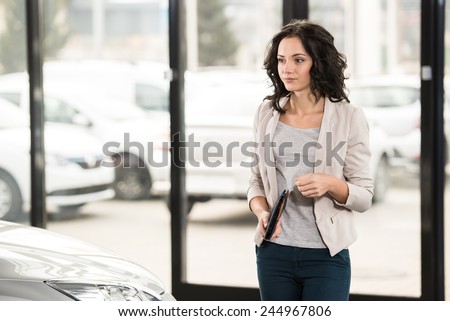 Attractive woman at car salon is choosing a car.