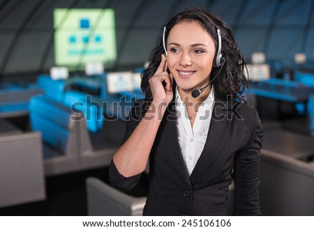 Portrait of a handsome young woman in earphones is standing in the background of the modern conference hall.