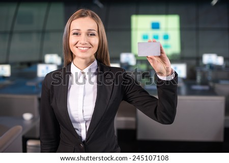 Portrait of a handsome young woman with discount card is standing in the background of the modern conference hall.