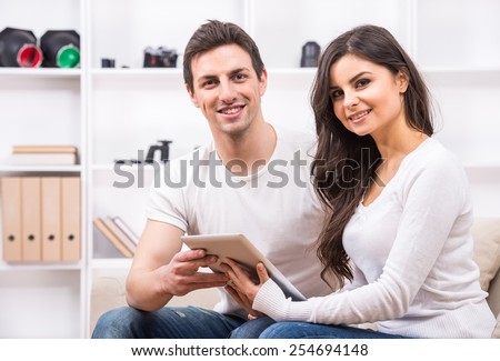 Young couple are using pc tablet to looking at photographs and looking at the camera.