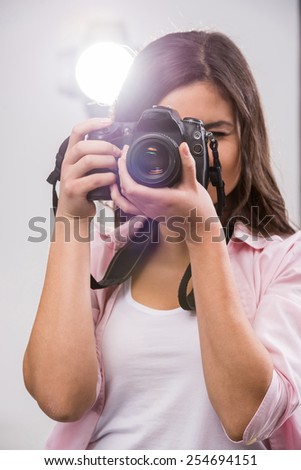 Young female photographer with camera in professionally equipped studio.