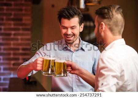 Two handsome friends in a pub with glasses of beer.