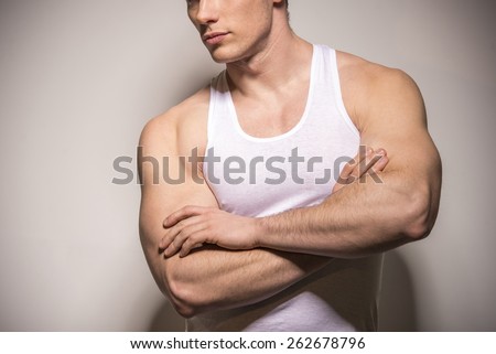 Crossed arms close up of muscular man on light background.