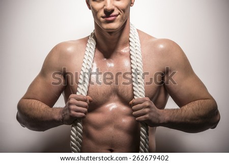 Close-up. Muscle young man on white background with white rope on neck.
