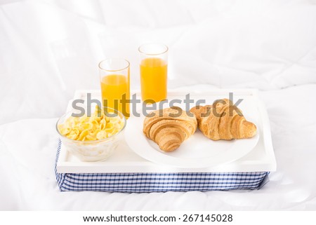 Breakfast tray laying on white bed in home.