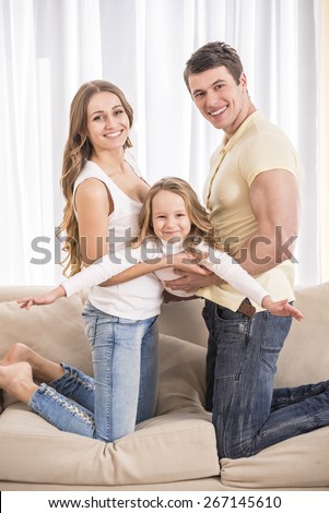 Mother, father and daughter. Portrait of happy family sitting on sofa.
