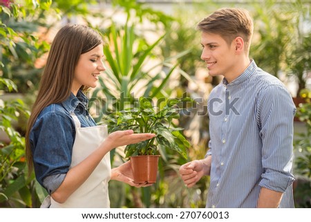 Female florist giving young male flower pot.