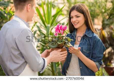 Male florist giving young female flower pot.