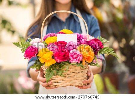 Close-up. Young female florist holding bouquet of flowers in shop. Focus on bouquet.