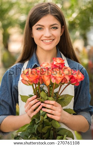 Portrait of young female florist holding bouquet with roses.