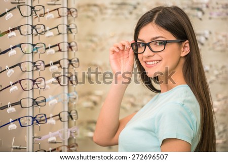 Young woman is choosing a glasses in optician store.