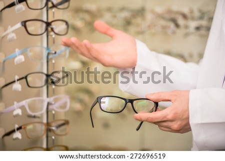 Young man (only hands) at optician with glasses is showing a glasses.