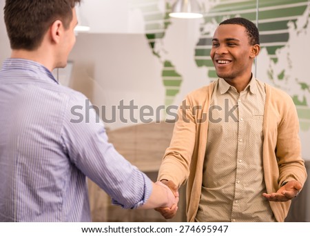 Smiling businessman handshaking with his colleague. Back view.