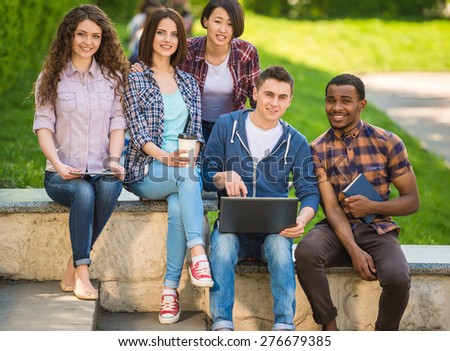 Group of young attractive smiling students dressed casual sitting on the staircase outdoors on campus at the university.