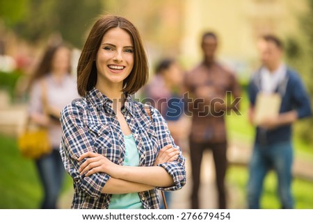 Young attractive smiling student outdoors on campus at the university with friends.
