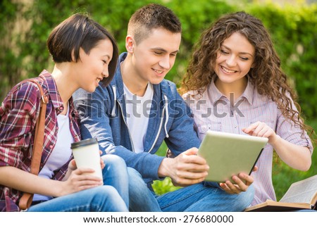 Young attractive smiling students dressed casual  studying outdoors on campus at the university.