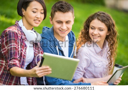 Young attractive smiling students dressed casual  studying outdoors on campus at the university.