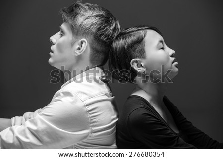 Young fashionable couple sitting back to back.  Black and white fashion portrait. Tenderness.