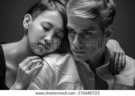 Young fashionable couple posing in the studio. Woman hugging man. Black and white fashion portrait. Tenderness.