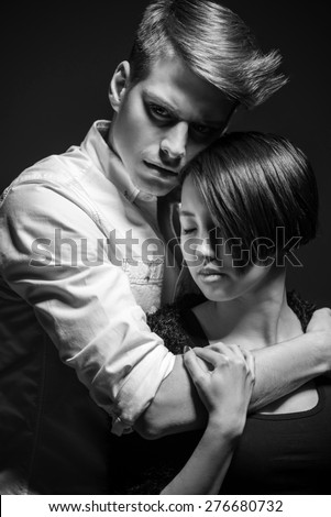 Young fashionable passionate couple dressed casual posing in the studio. Man hugging woman. Black and white fashion portrait.