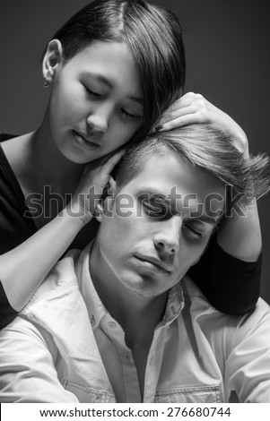Young fashionable couple posing in the studio. Woman hugging man. Black and white fashion portrait. Tenderness.