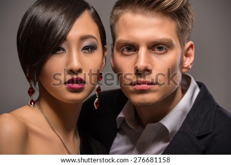 Young fashionable couple dressed in formal clothing posing in the studio on dark background. Fashion portrait.