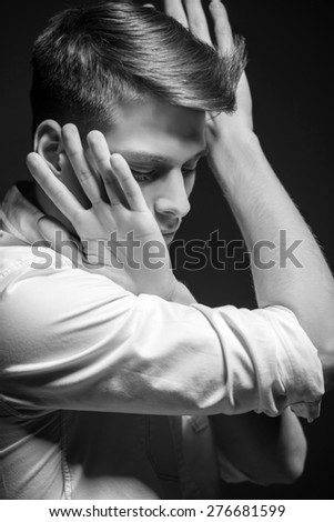 Young handsome man dressed casual posing in the studio on dark background. Black and white fashion portrait.