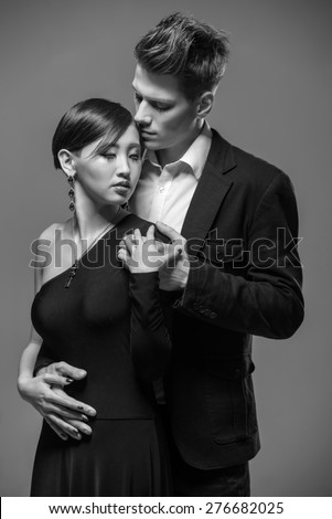 Young fashionable couple dressed in formal clothing posing in the studio. Black and white fashion portrait. Passion.