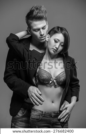Young fashionable couple in tuxedos  posing in the studio. Black and white fashion portrait. Passion.