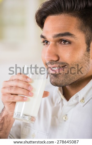 Young handsome man in white shirt drinking glass of milk for breakfast.