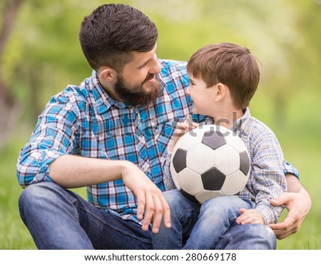 Young father with his little son having fun on football pitch.