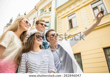 Double couple date. Friends walking down the street together and making selfie.