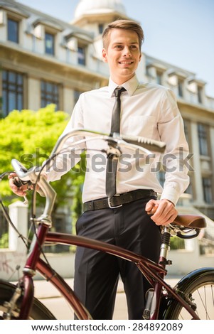 Portrait of young businessman riding bicycle to work on urban street.