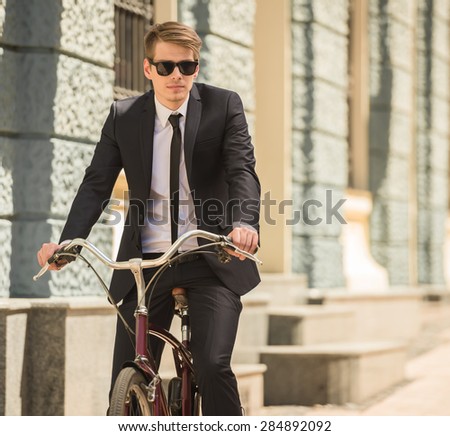 Portrait of young businessman riding bicycle to work on urban street.
