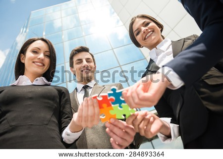 Closeup of business people wanting to put four pieces of puzzle together. Team work.