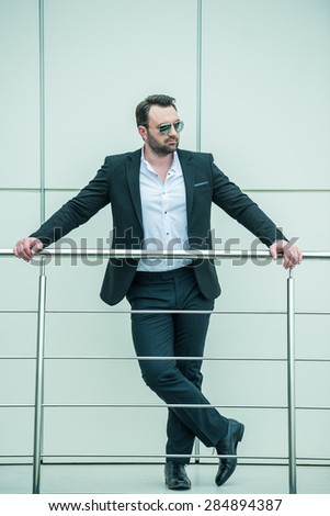 Handsome successful businessman standing on stairs of modern office.