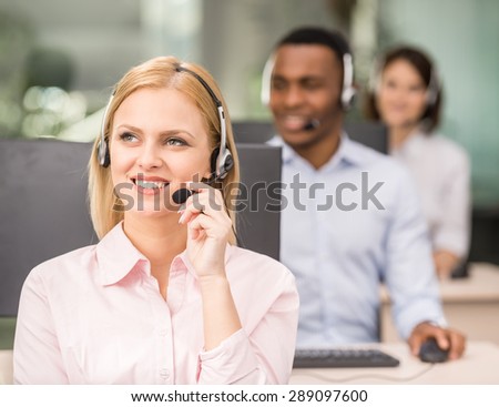 Beautiful young lady talking on headset at call center office.