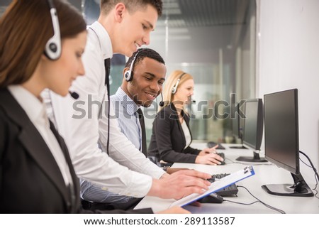 Manager explaining something to his employee in a call centre.
