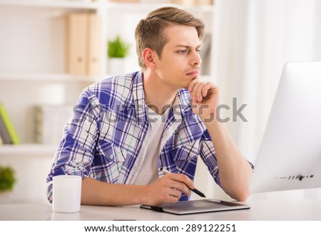 Young male programmer dressed casual sitting at the table and using computer.