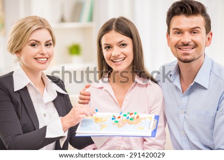 Female travel agent greeting happy young couple at office.