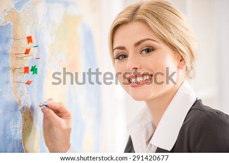 Beautiful woman standing near map with destination signs on it.