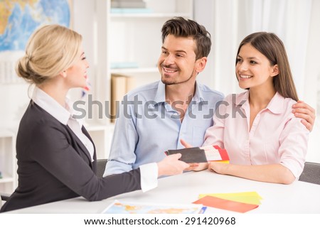 Female travel agent giving tickets to young happy couple.