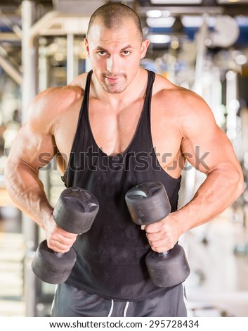 Handsome power athletic man bodybuilder doing exercises with dumbbell. Fitness muscular body.